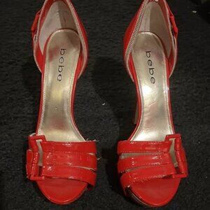 This is a pair of red women's high-heel sandals from the bebe brand.